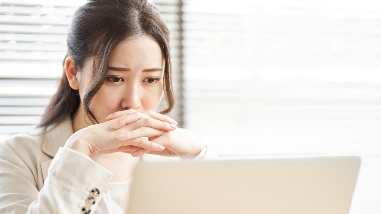 PCの前で悩む女性